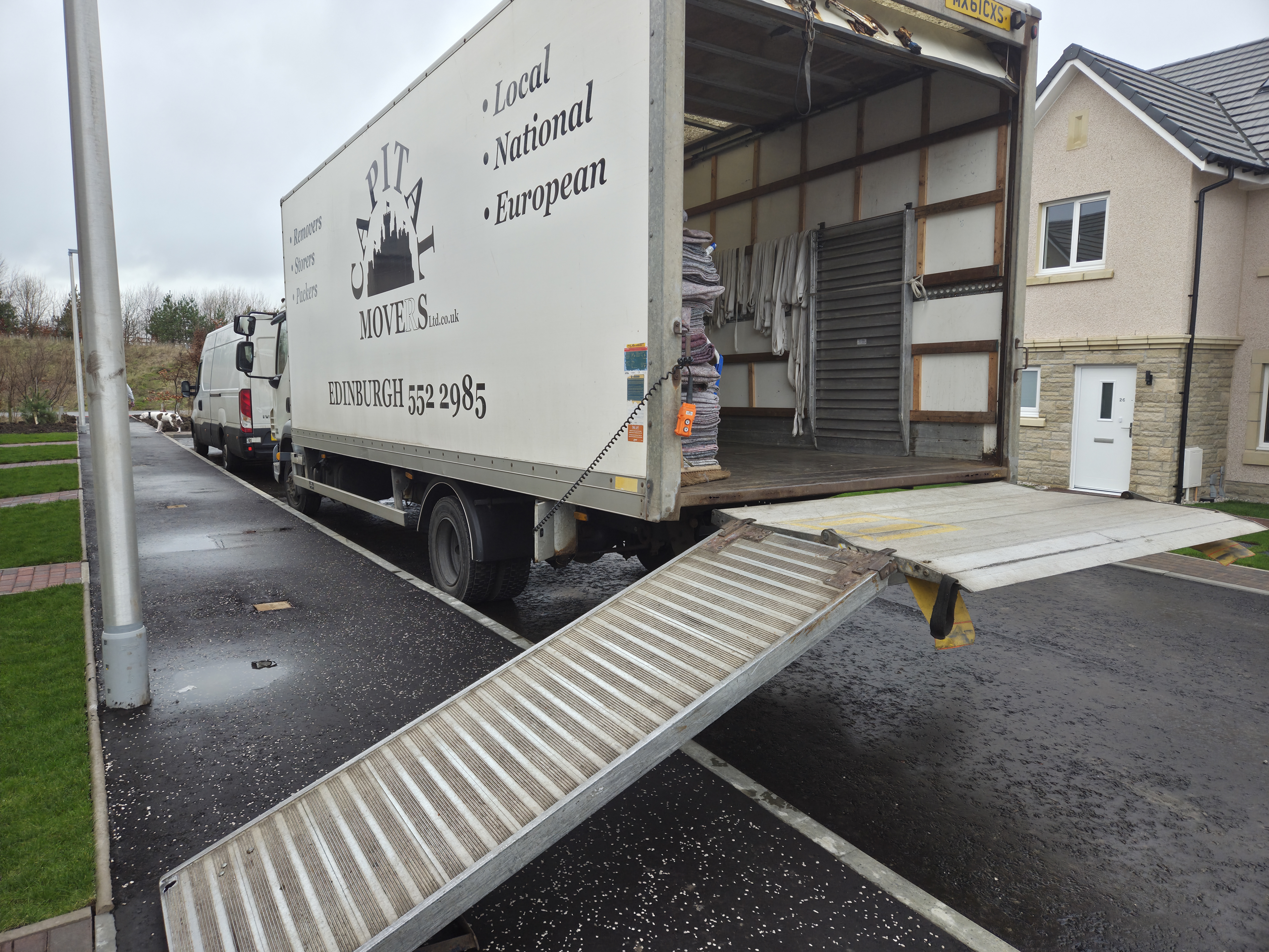 Capital Movers Edinburgh removal lorry with loading ramp extended at a modern house driveway for secure storage delivery